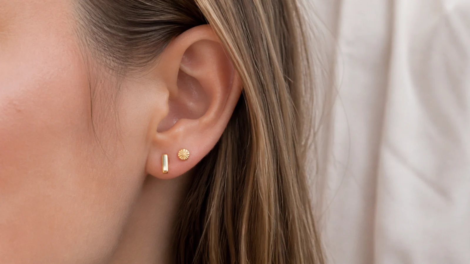 Faceless close-up of gold vermeil stud earrings on an ear, an affordable tarnish-resistant pick under fifty dollars