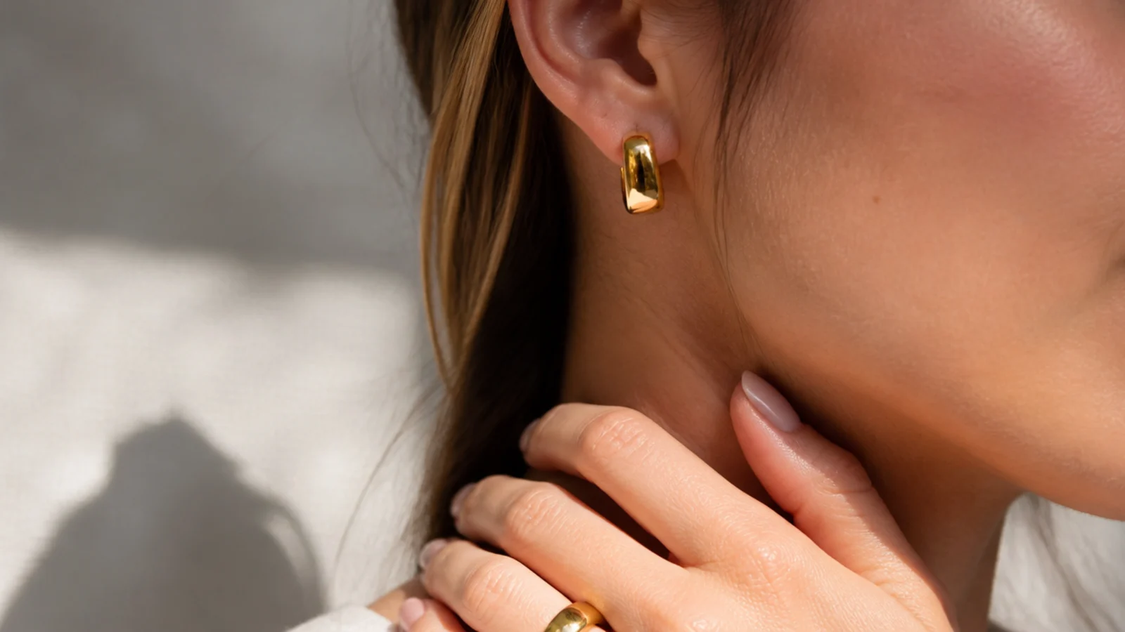 Faceless close-up of chunky gold vermeil bold huggie hoops, a demi-fine pick that reads expensive under fifty dollars