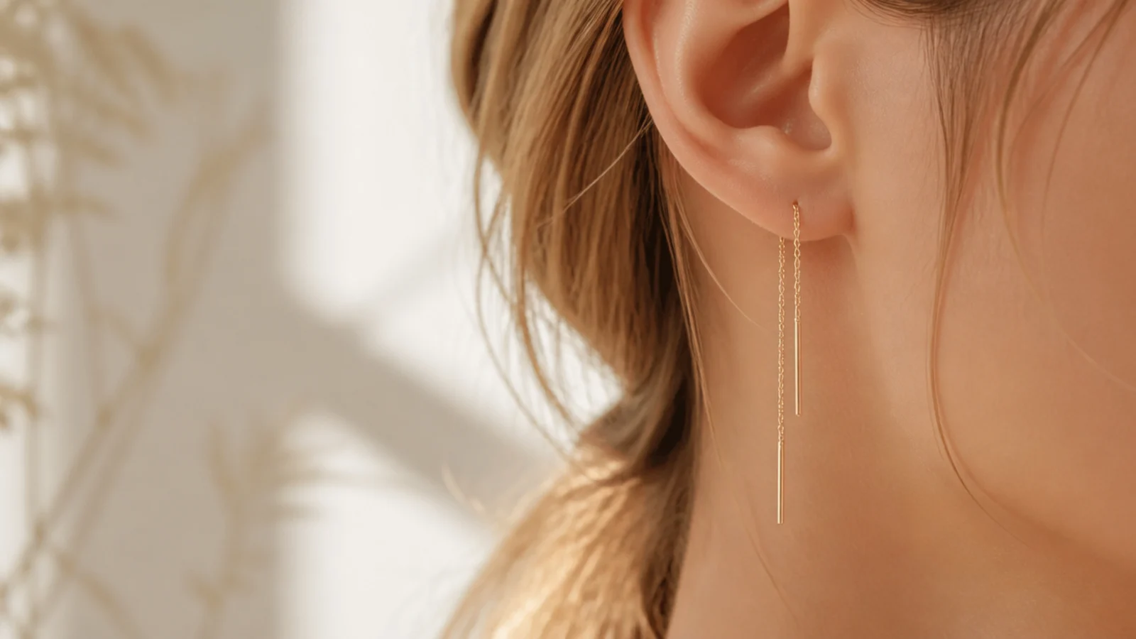 Faceless close-up of delicate gold vermeil chain threader earrings, a dainty demi-fine pick under fifty dollars