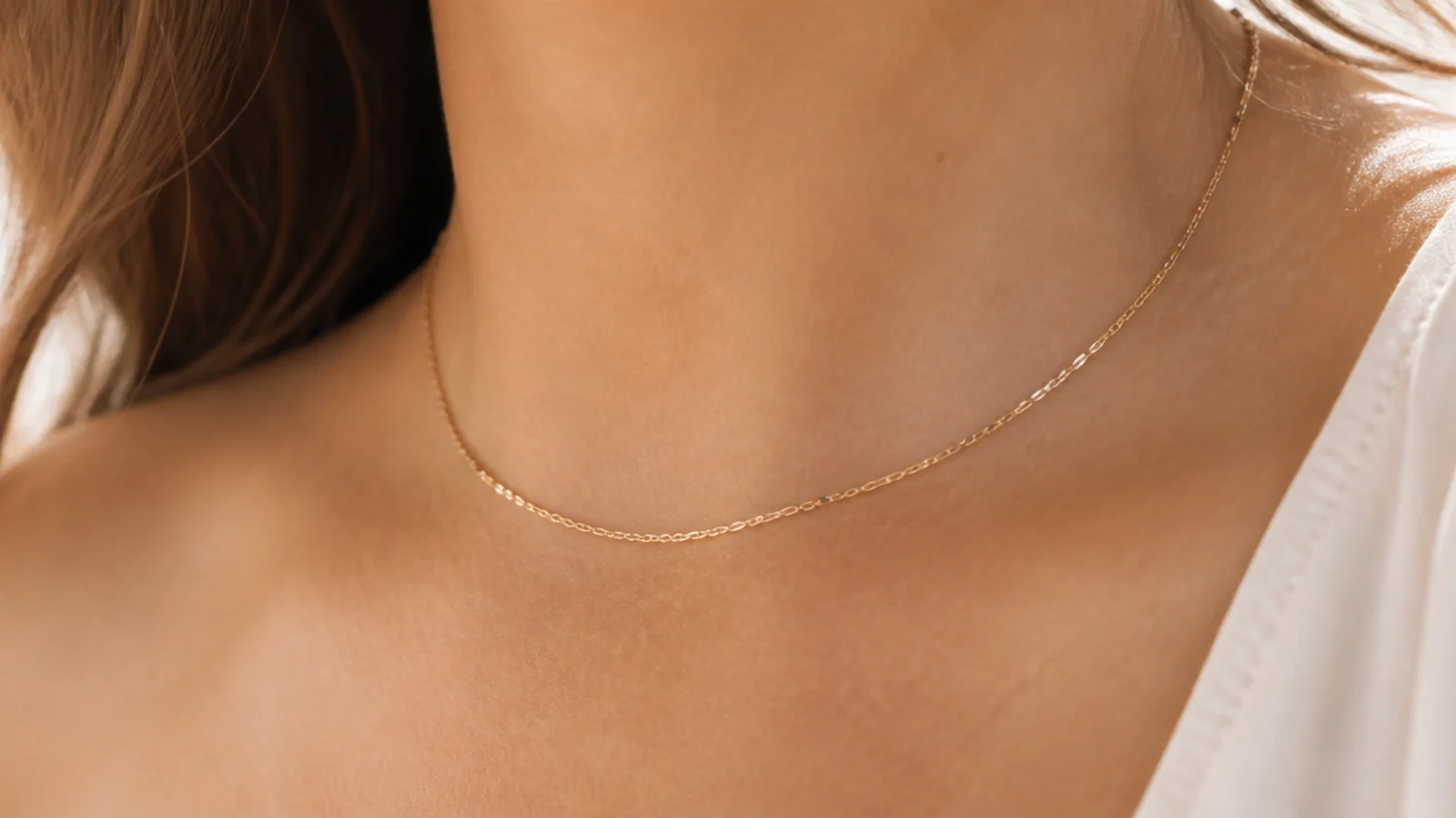 Faceless close-up of a thin gold-filled layering chain necklace, a waterproof tarnish-resistant pick under fifty dollars