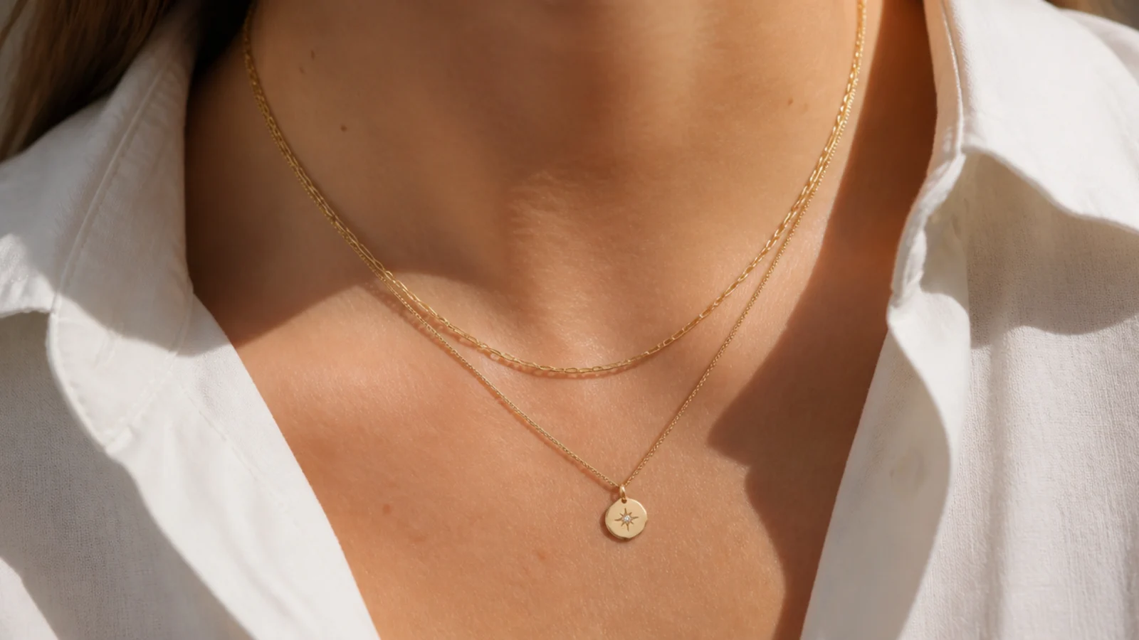 Faceless close-up of a gold-filled layering necklace with a small charm, a durable pick under fifty dollars
