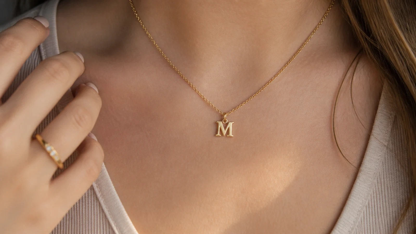 Faceless close-up of a gold vermeil initial pendant necklace, a personalized demi-fine pick under fifty dollars