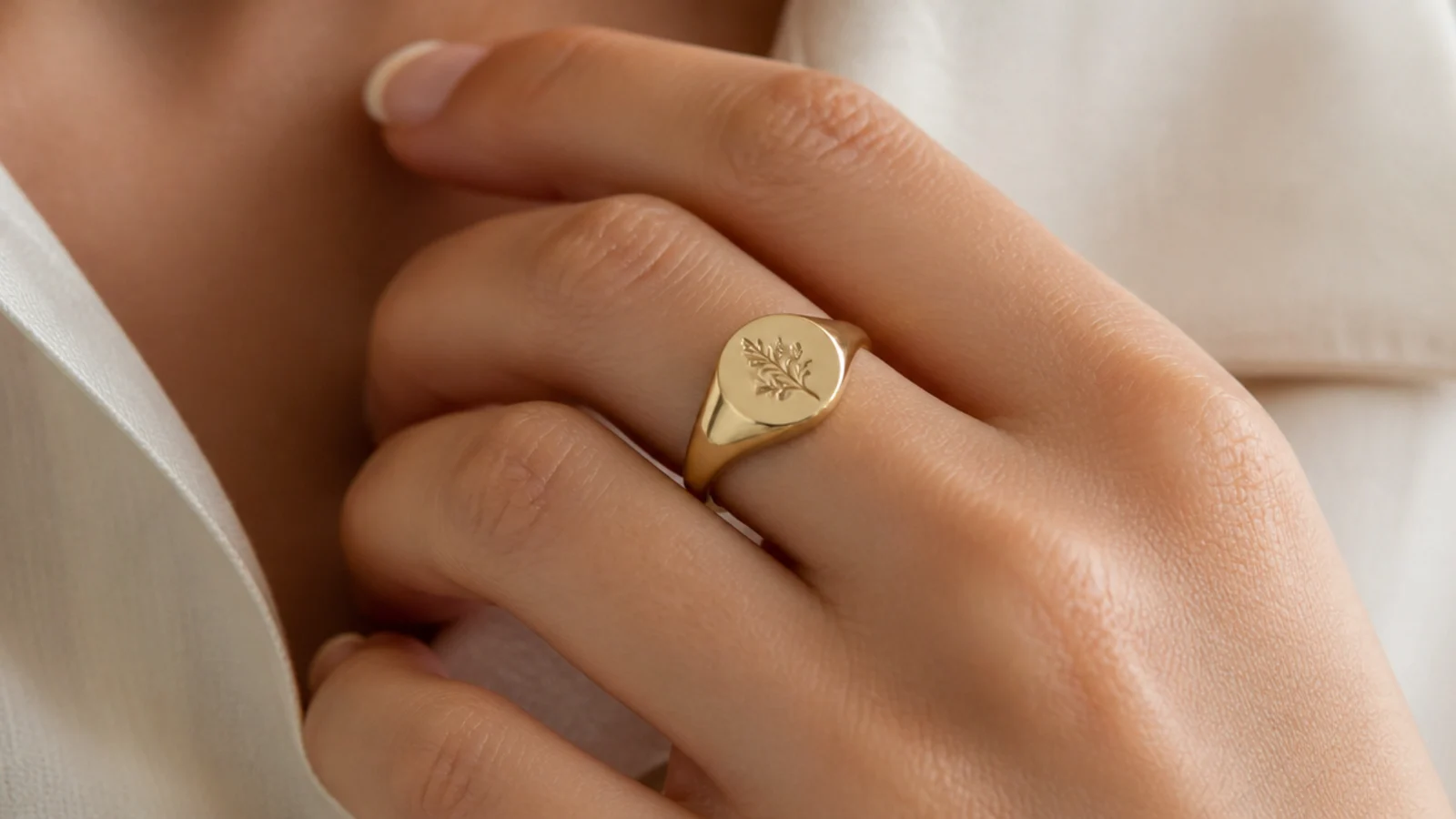 Faceless close-up of a gold vermeil signet ring on a finger, an affordable statement pick just under fifty dollars