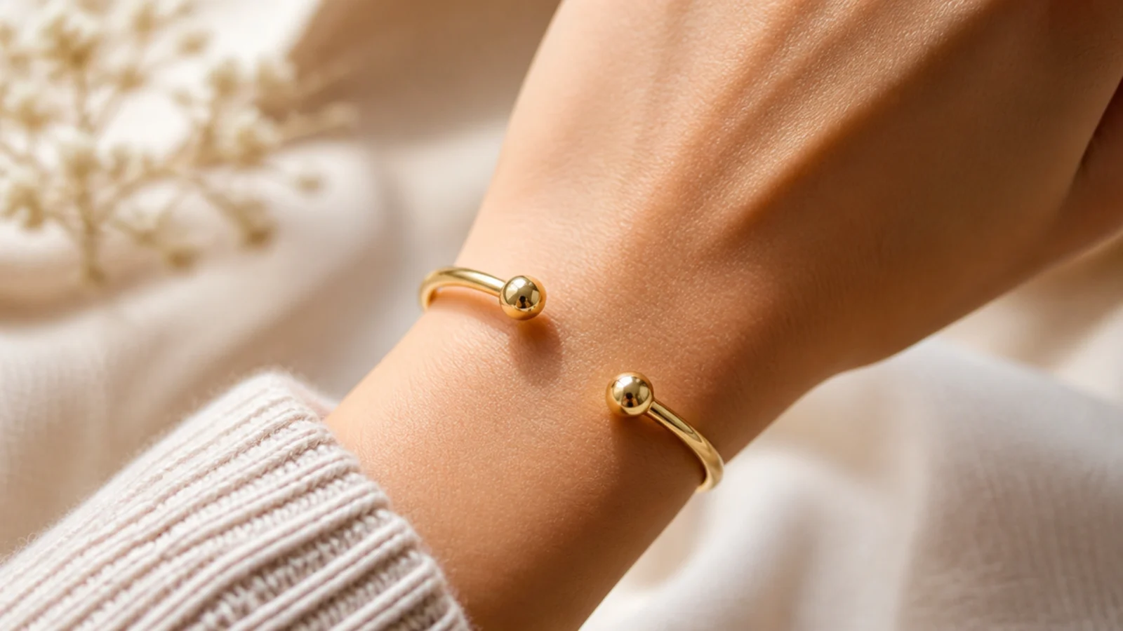 Faceless close-up of a smooth gold-plated open cuff bracelet on a wrist, a budget statement pick under fifty dollars