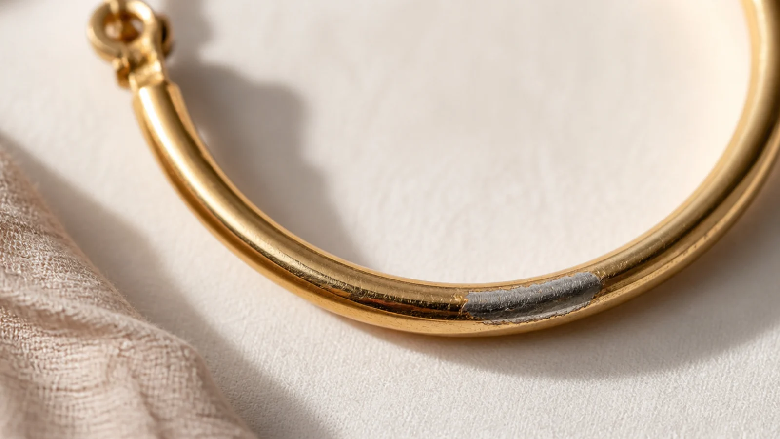 Faceless macro of a gold-plated hoop showing worn thin gold revealing brass underneath