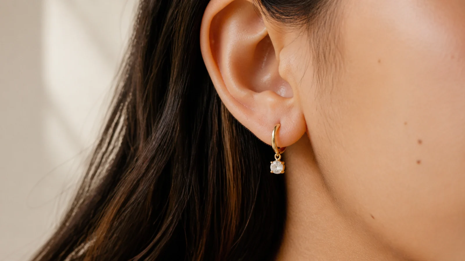 Faceless close-up of a nickel-free gold vermeil earring on a sensitive earlobe with no irritation