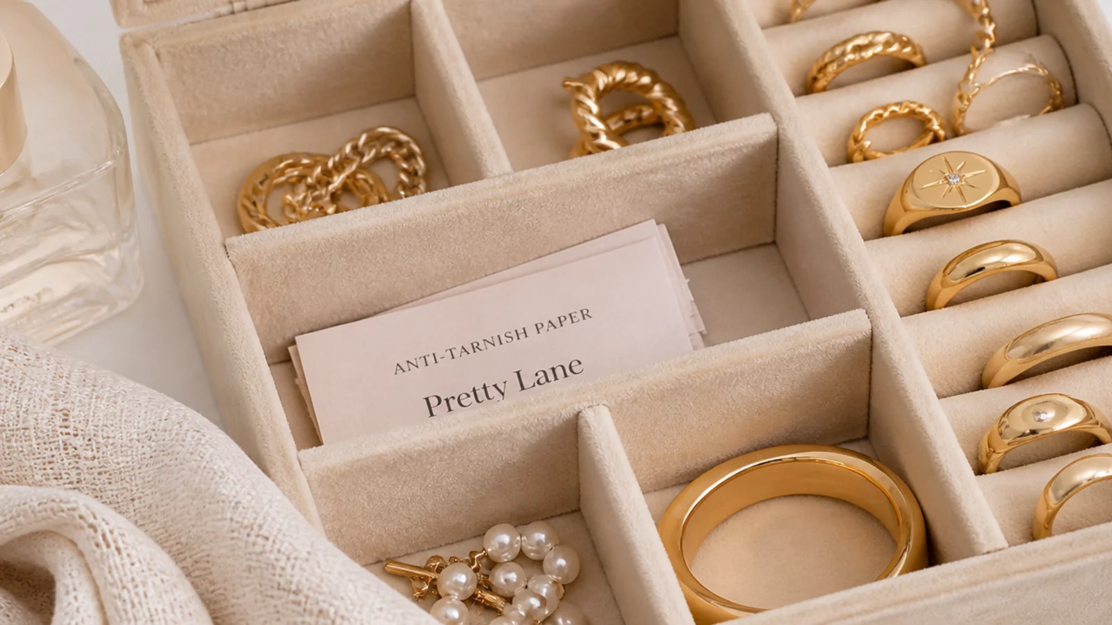 Faceless close-up of small anti-tarnish paper strips tucked into a compartment jewelry box with gold pieces