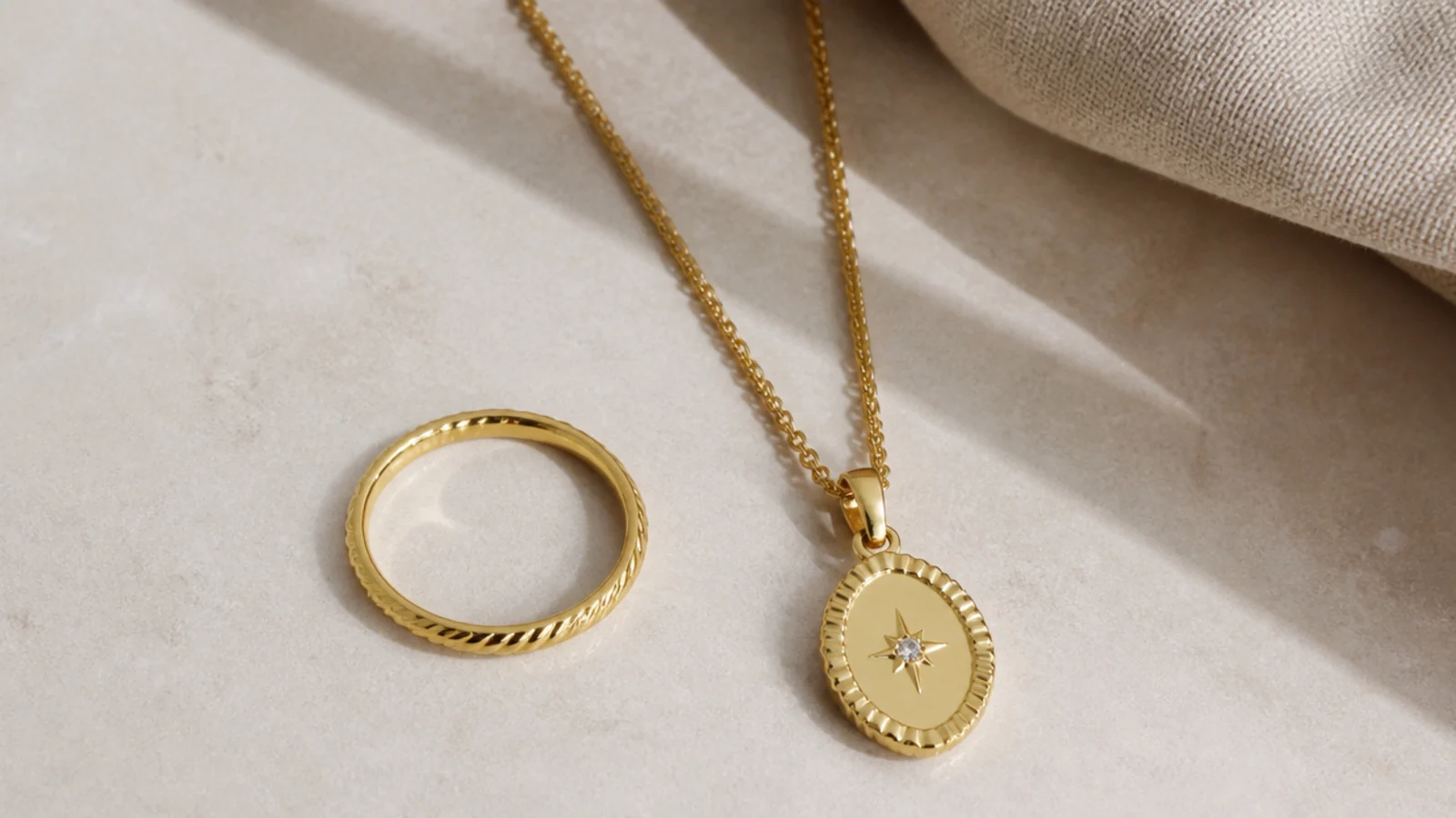 Faceless flat lay comparing a solid gold ring beside a gold vermeil necklace on a neutral surface