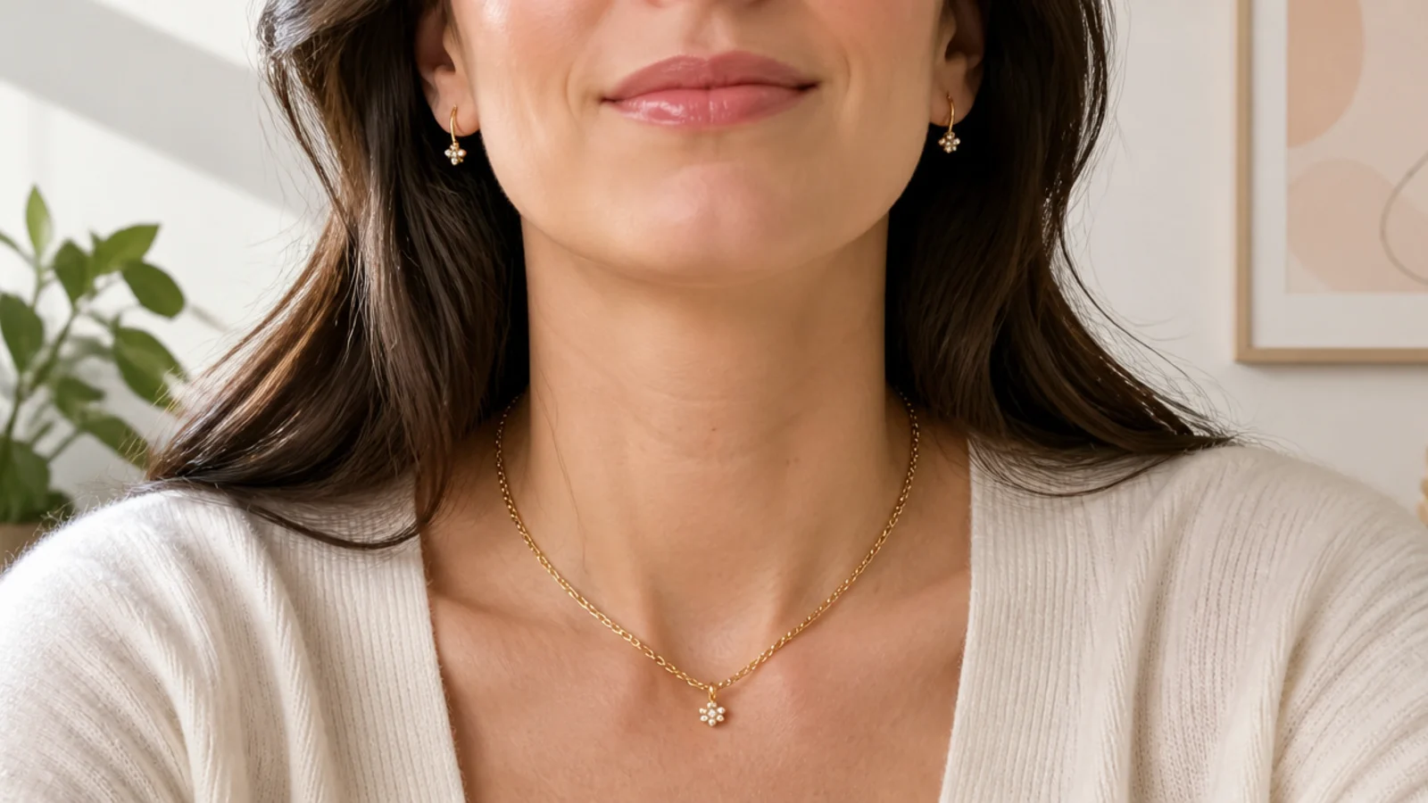 Faceless bust-crop view of small gold earrings and a short necklace framed as they appear on a video call