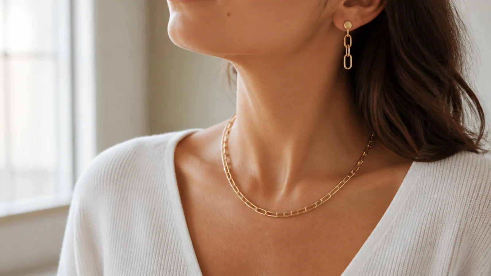 Faceless bust-crop showing earrings and a short necklace positioned to appear on a video call