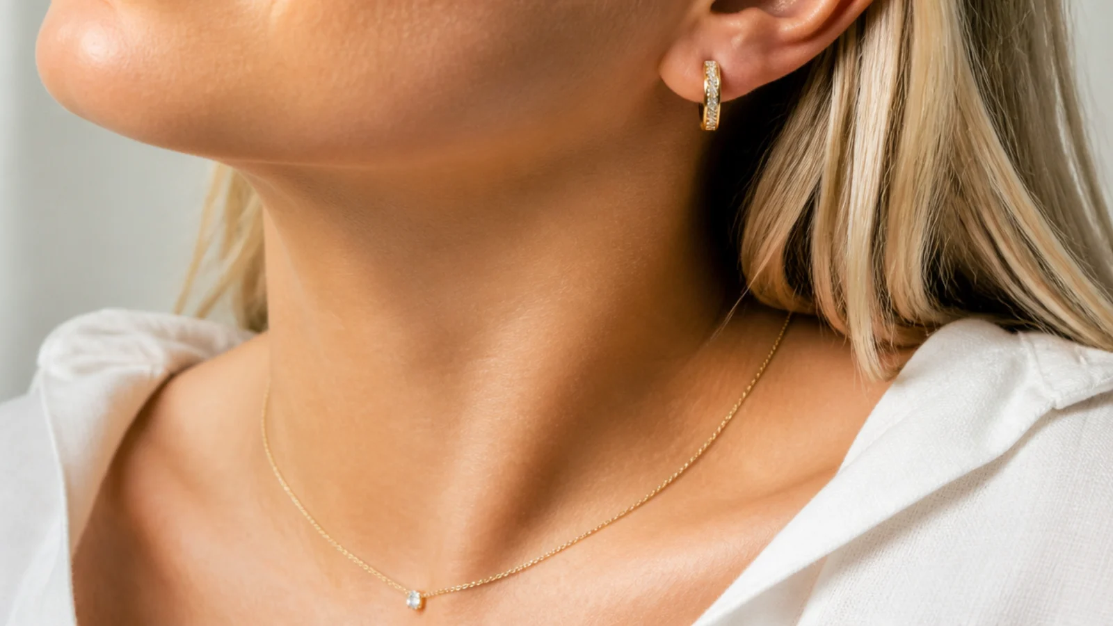 Faceless bust-crop showing which jewelry appears on a video call, earrings and top of a necklace only