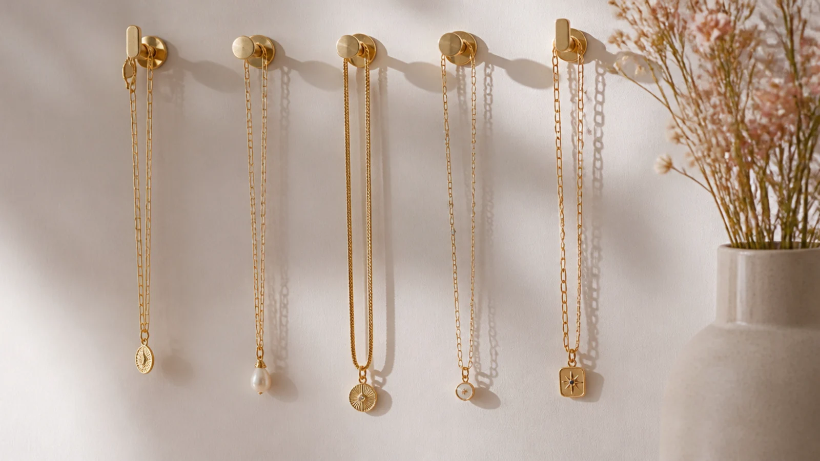 Faceless shot of necklaces hanging separately from a row of small hooks mounted on a wall