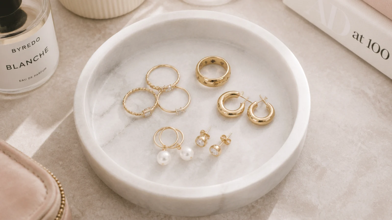 Faceless overhead shot of a shallow marble tray on a vanity holding daily-rotation rings and earrings