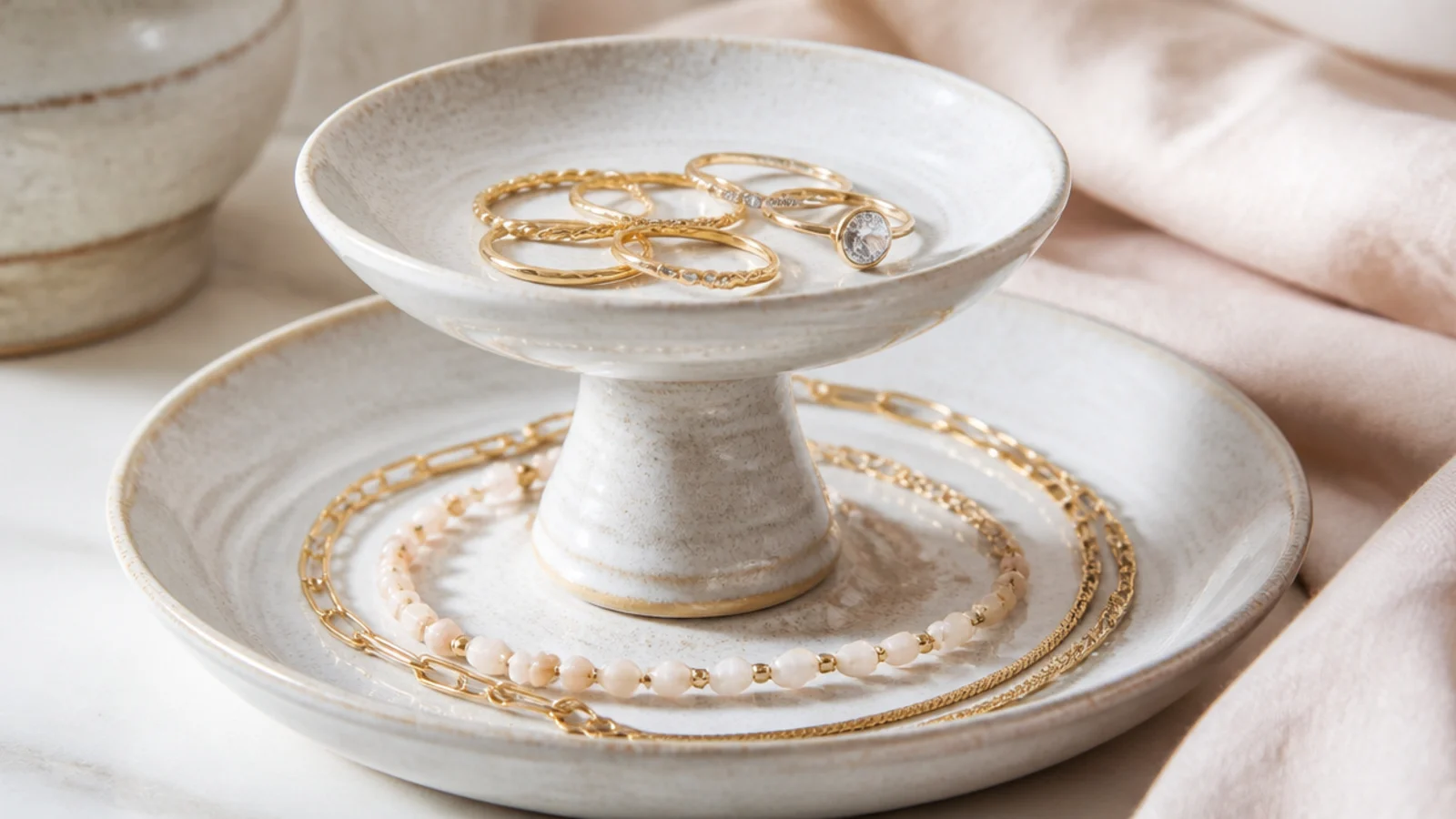 Faceless shot of a two-tier ceramic cake stand repurposed to display rings on top and bracelets below