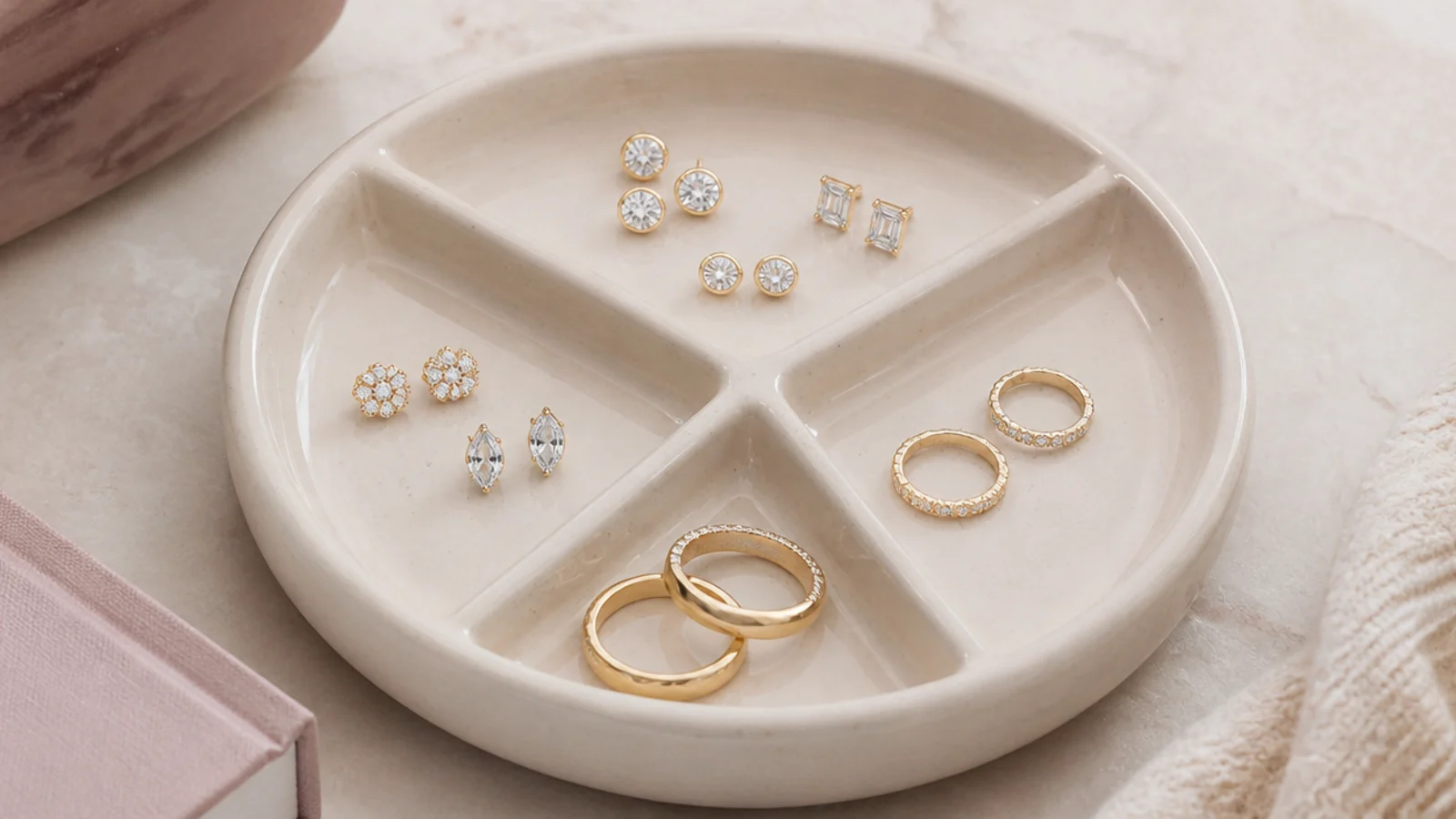 Faceless overhead shot of a ceramic divided dish holding pairs of stud earrings and small rings by section