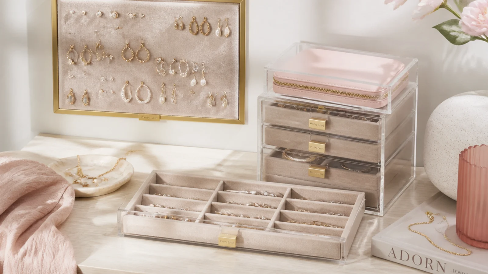 Faceless flat-lay of small-space jewelry storage with a wall earring board, stacked acrylic drawer and slim drawer insert