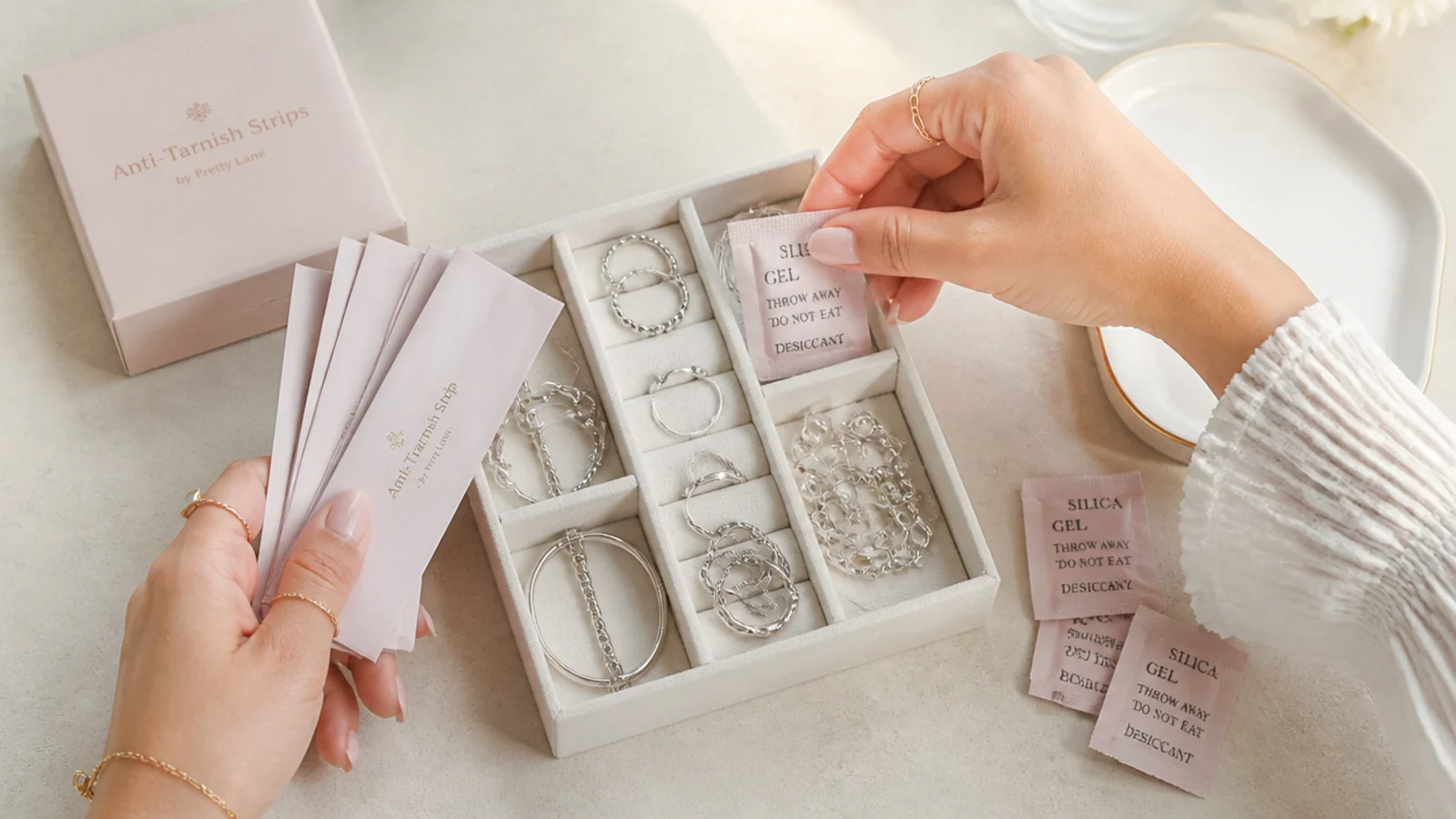Faceless overhead shot of anti-tarnish strips and silica packets being added to a compartment box of silver
