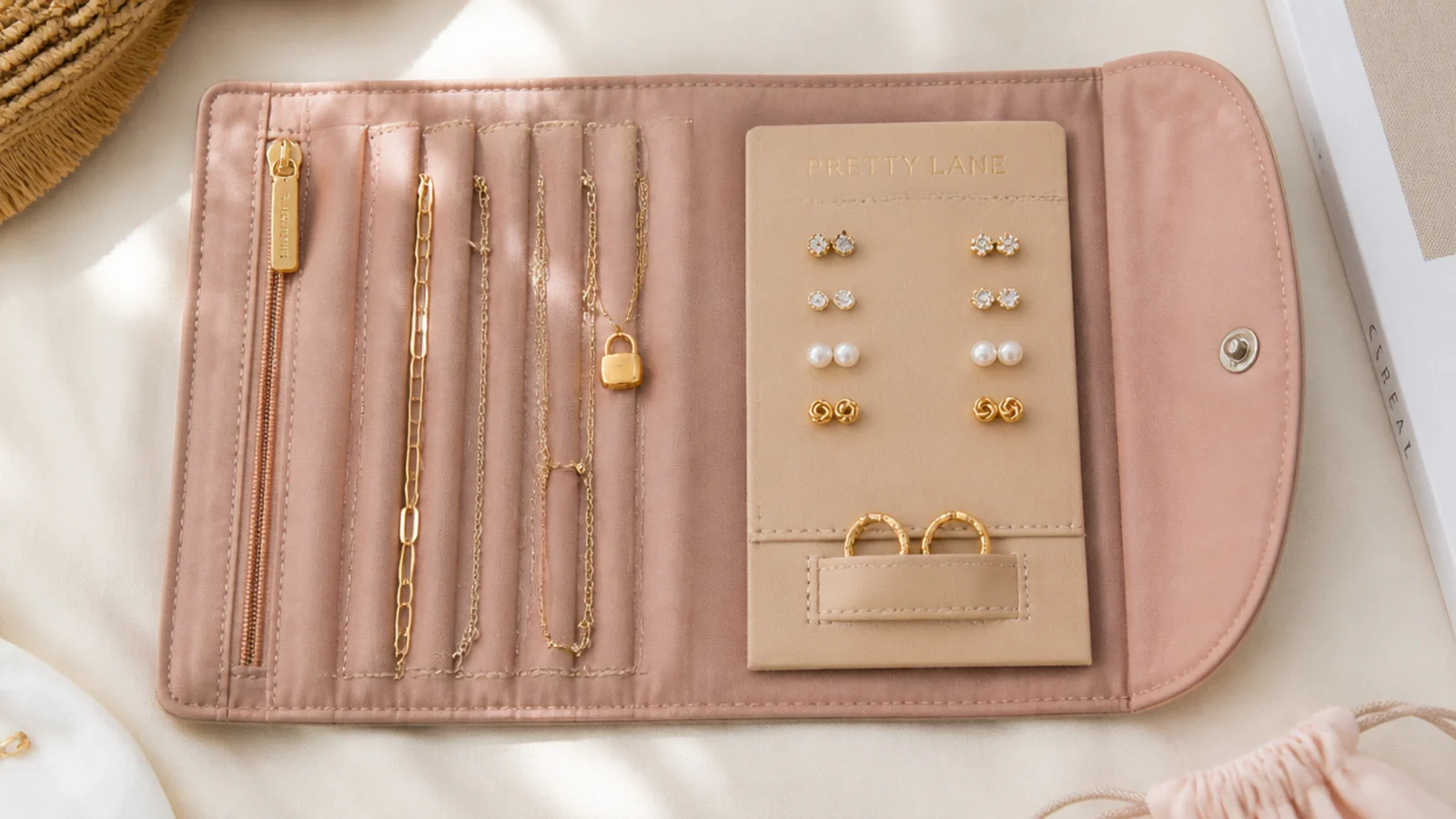 Faceless overhead shot of a packed travel jewelry roll with a button card of studs and chains threaded through straws