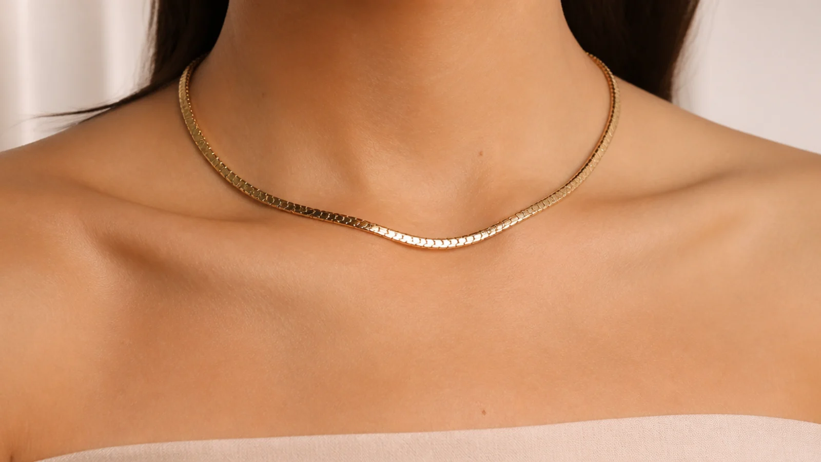 Faceless close-up of a gold collar necklace filling the open expanse of a strapless neckline