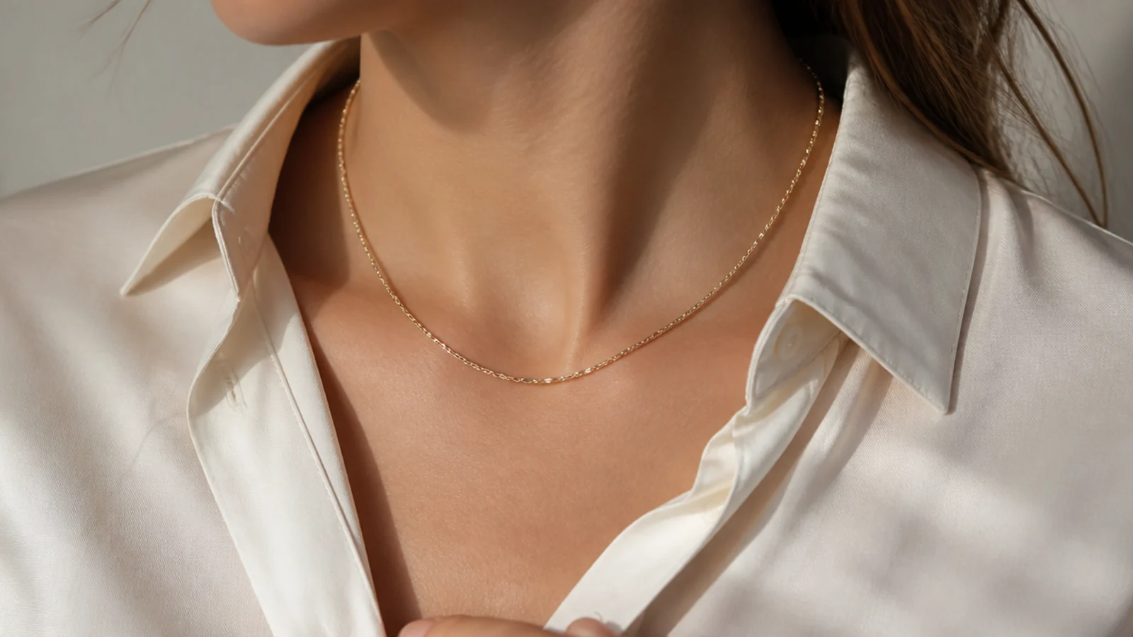 Faceless close-up of a short 16-inch gold chain worn inside an open button-down shirt collar