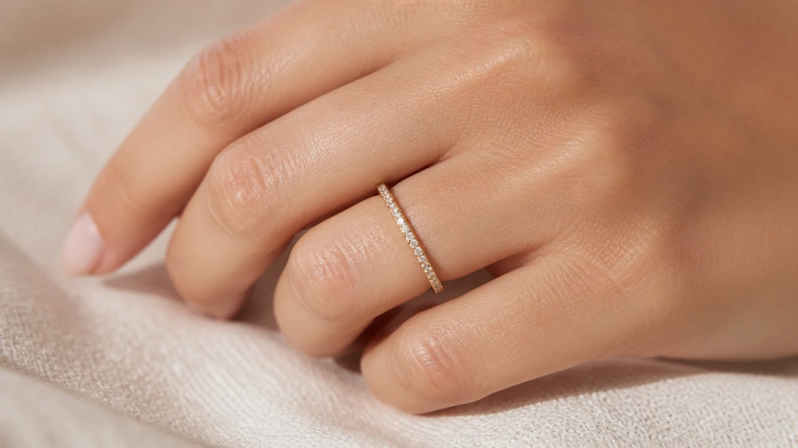 Faceless close-up of a thin pave-set eternity band with tiny stones circling a gold ring