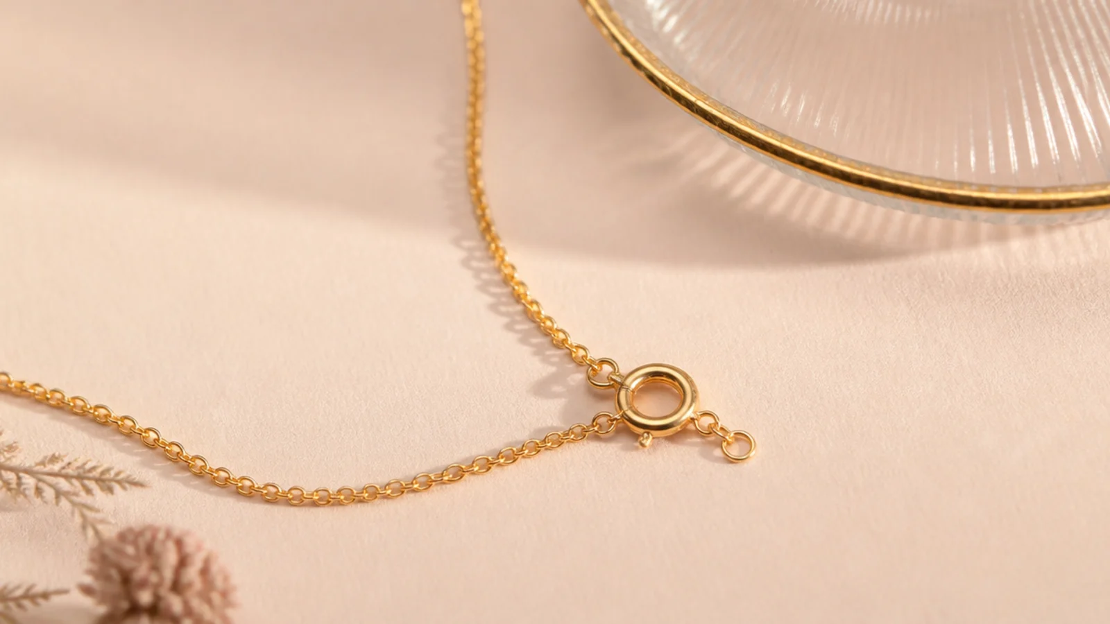 Faceless close-up highlighting a flimsy jump-ring clasp and orange-toned plating on a thin chain