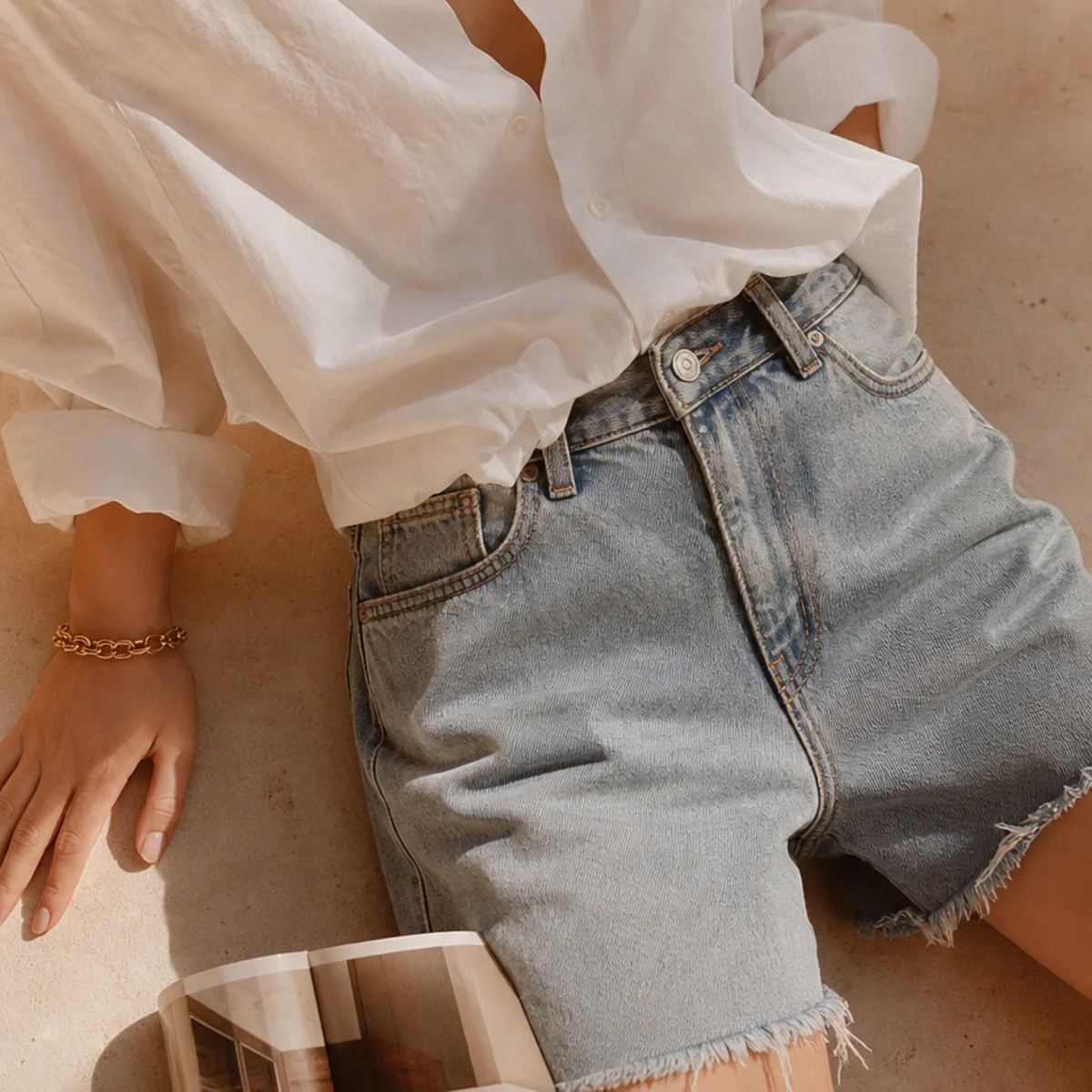 Faceless waist-up shot of an oversized button-down half-tucked into jorts with white trainers