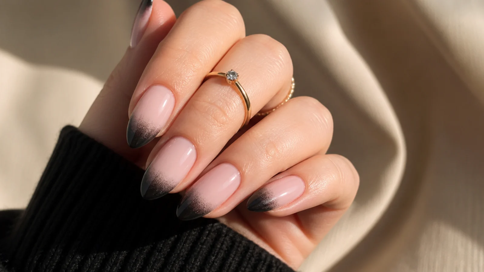 Almond nails with a smoky black airbrushed French tip fading into a sheer nude base