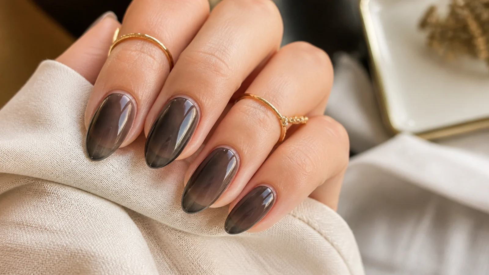 Sheer jelly black almond nails showing the natural nail through a translucent smoke gray overlay