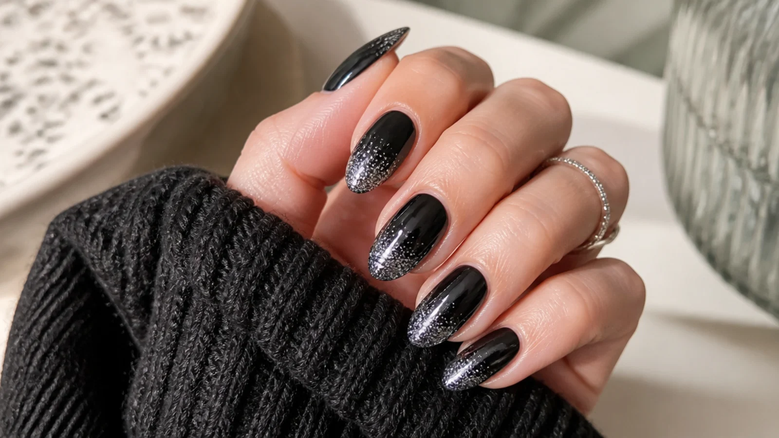 Black almond nails with silver glitter fading from the tip toward the cuticle