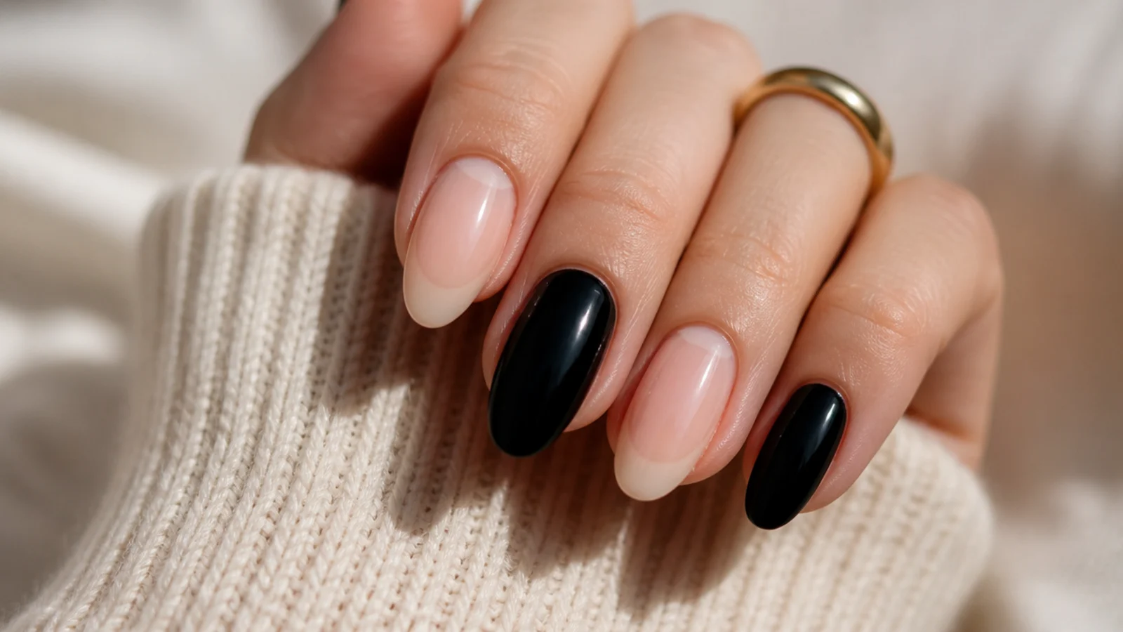 Almond nails alternating between a bare nude base and solid glossy black nails