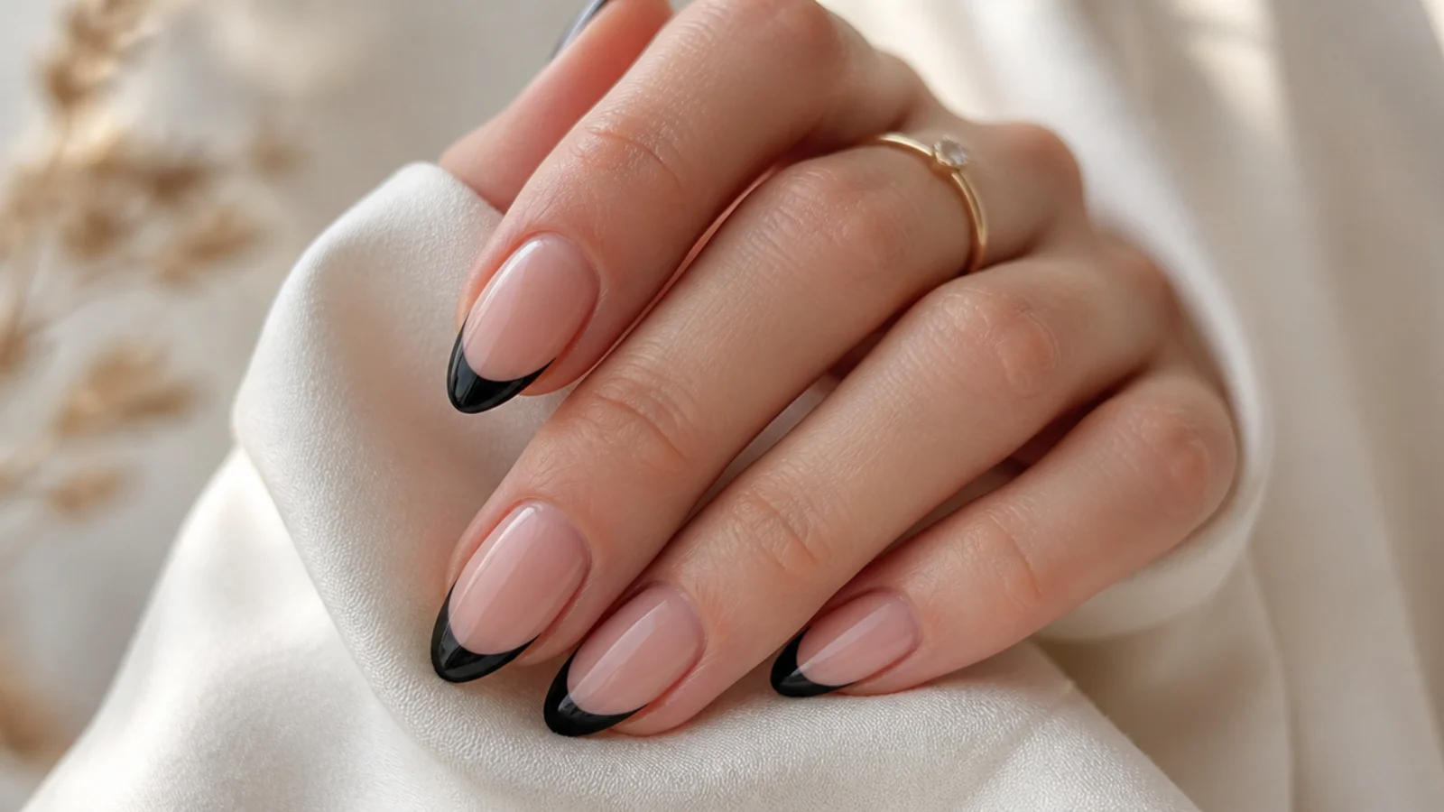 Almond nails with solid black French tips over a sheer pink base and curved smile lines