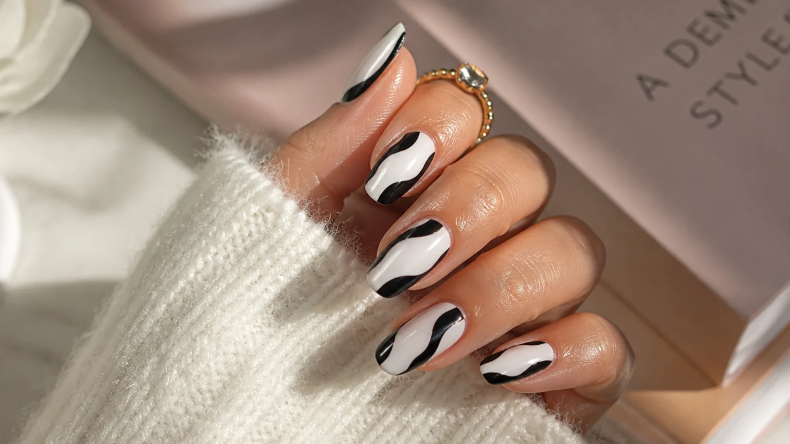 Almond nails with wide black swirls curving across a milky white base