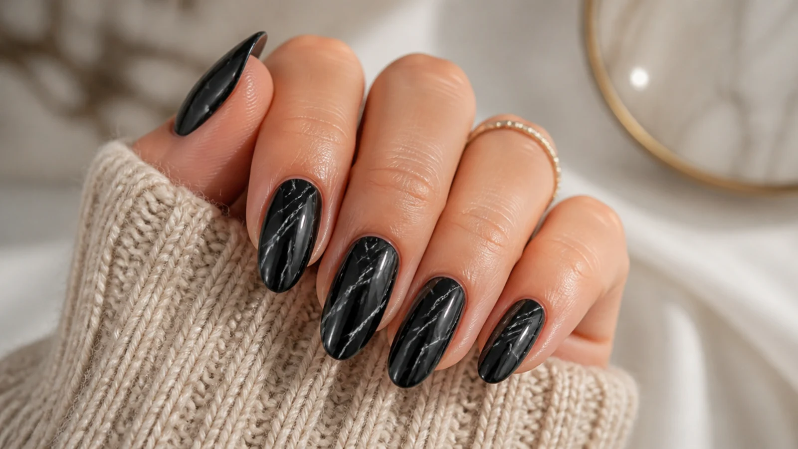 Black marble almond nails with thin gray and white veining running diagonally across each nail