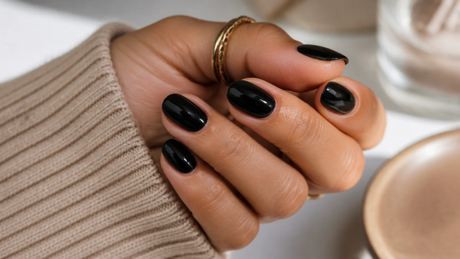 Short glossy black almond nails at about four millimeters with a soft rounded taper