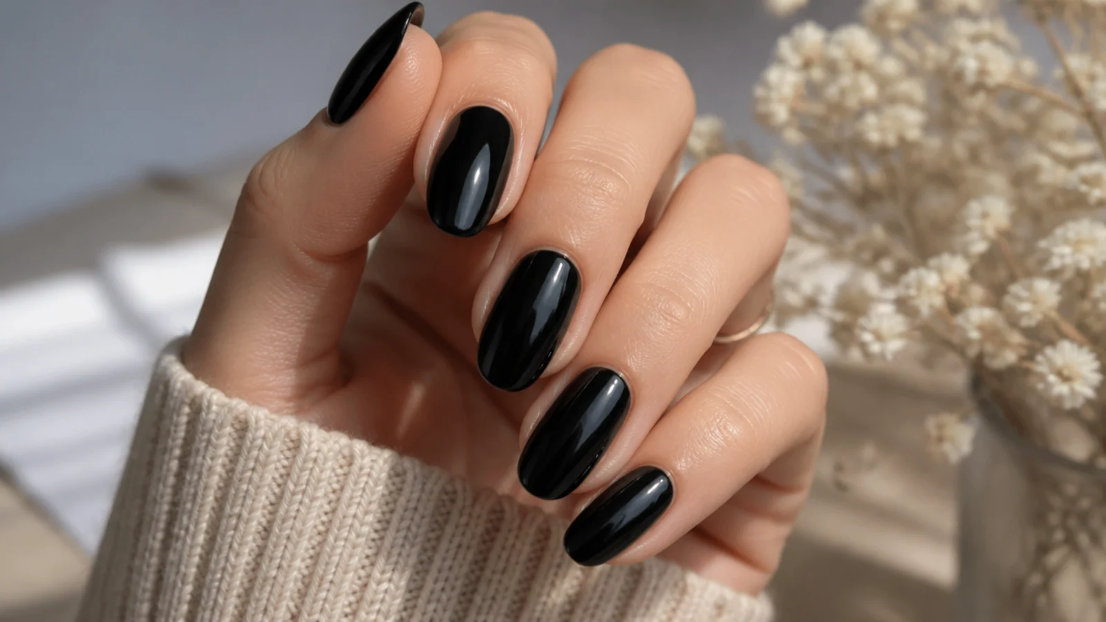 Medium length glossy black almond nails with a soft tapered tip and high shine top coat