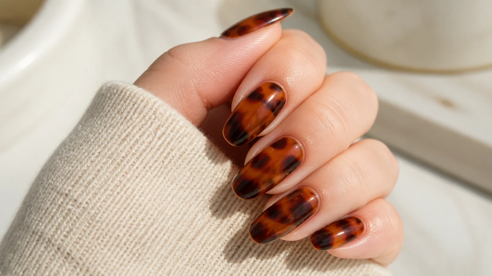 Long oval nails with amber and dark brown mottled tortoiseshell patches under gloss