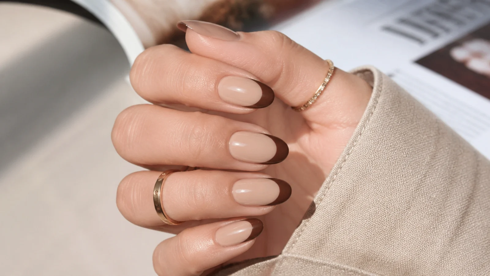 Medium oval nails with a chocolate brown curved french tip over a warm beige base