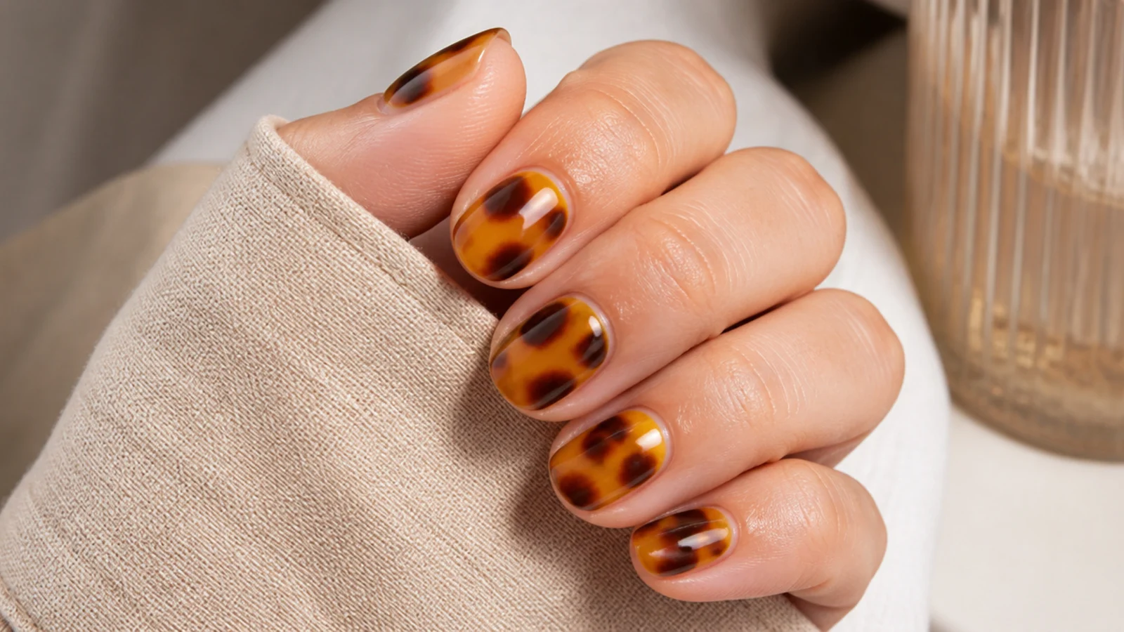 Short almond nails in mottled amber and dark brown tortoiseshell over a honey base