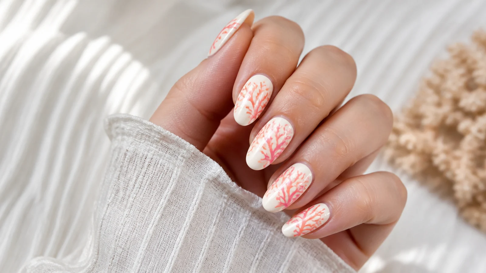 Medium almond nails with branching coral reef shapes in orange and pink over a cream base
