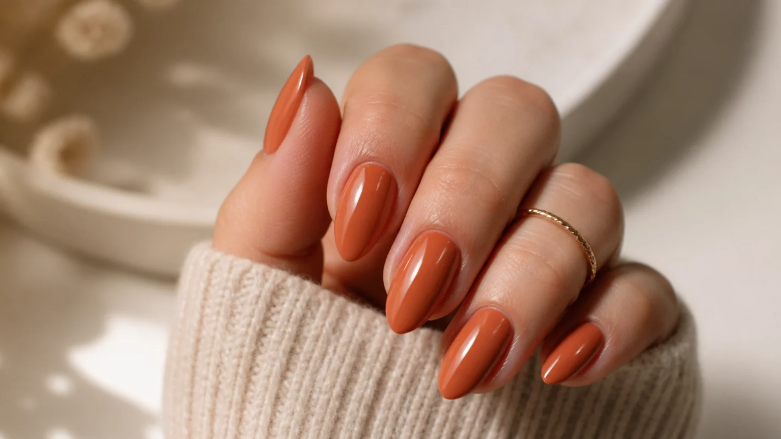 Medium almond nails in warm terracotta clay orange with a glossy finish