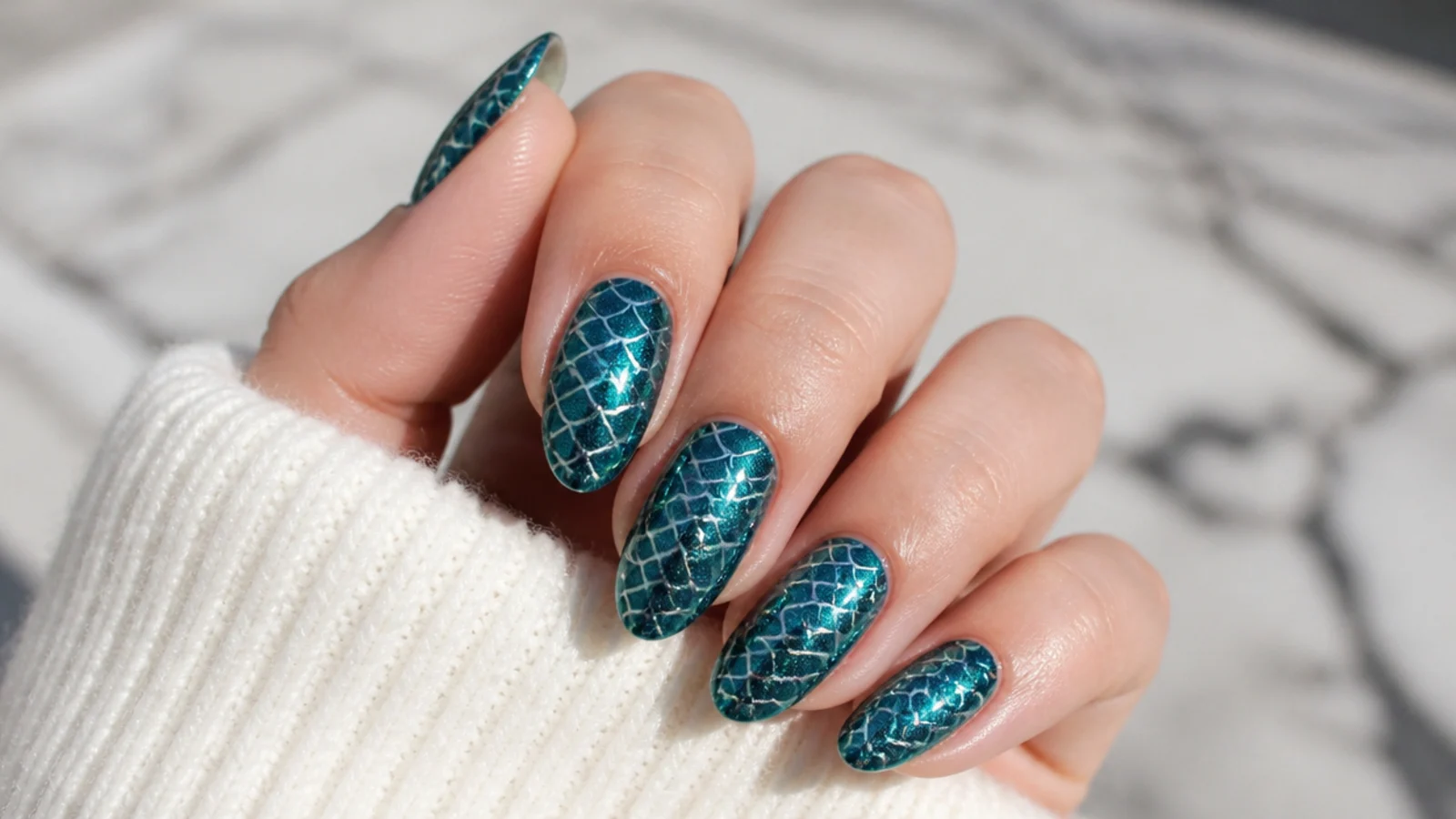 Almond nails with an aqua chrome scale pattern stenciled over a teal base