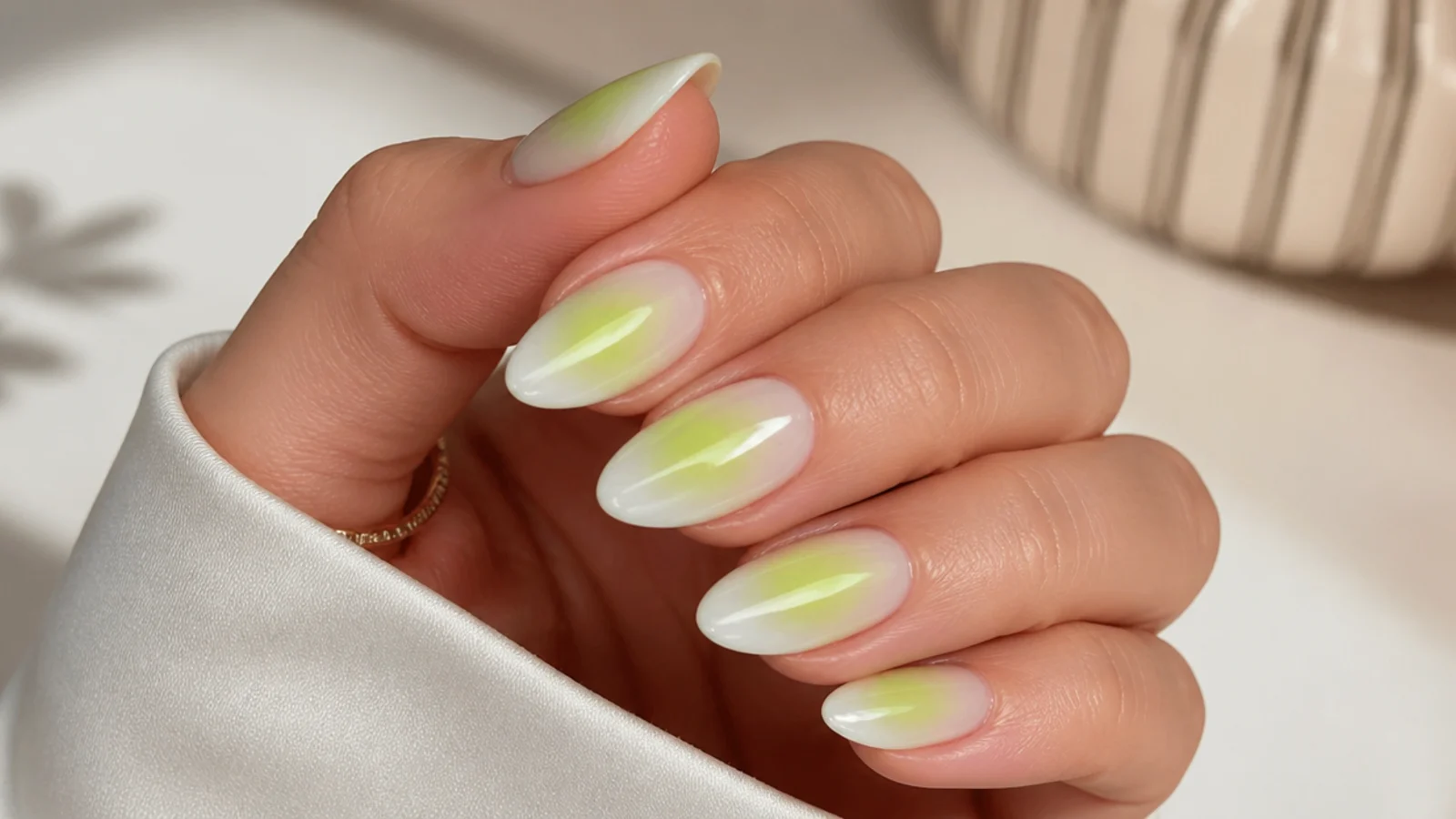 Almond nails with a lime green aura halo airbrushed into the center of a milky base