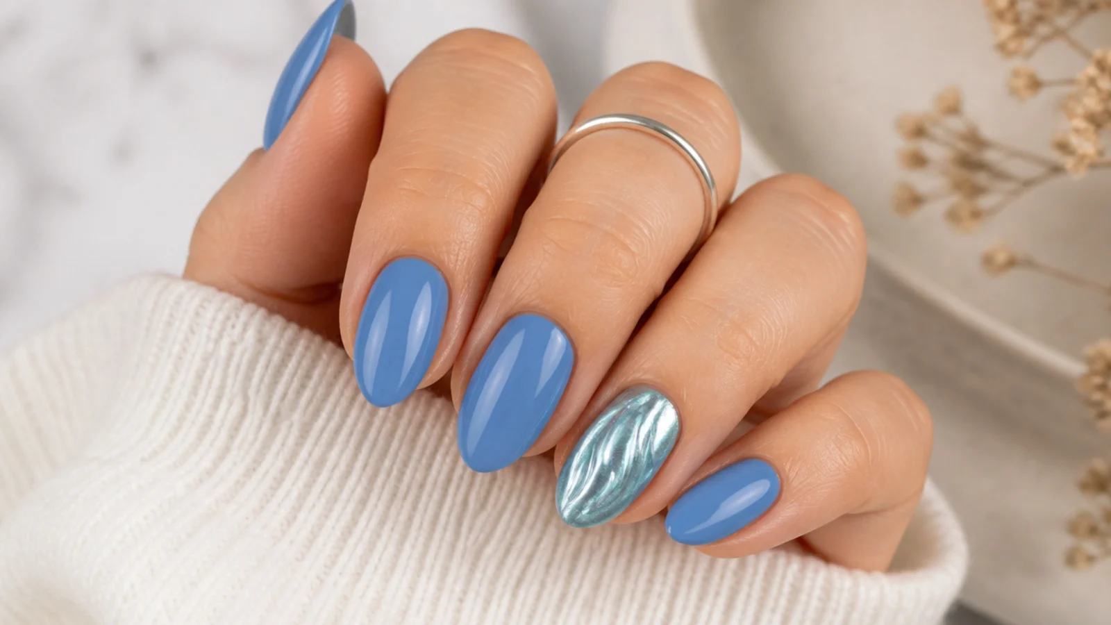 Medium blue nails with one aqua chrome accent nail shaped like a shimmering metallic wave