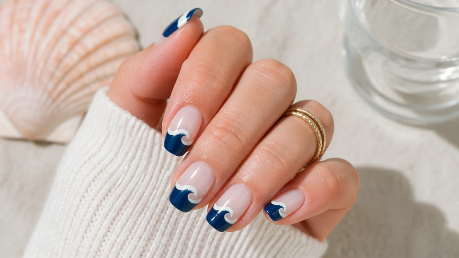 Medium nails with a navy French tip shaped as a curling wave with a white foam smile line