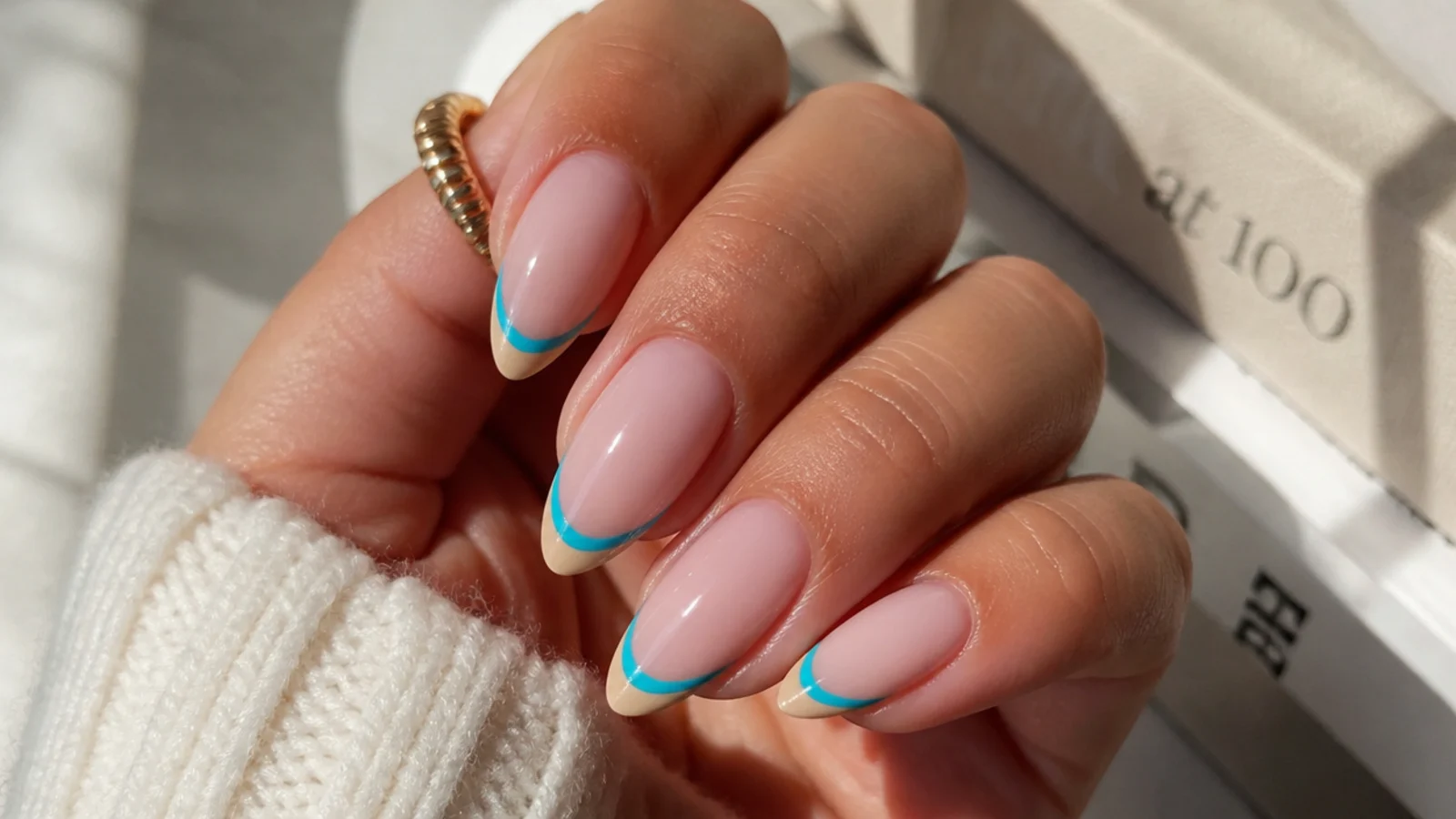 Almond nails with a double French tip in turquoise over a sandy beige band at the edge
