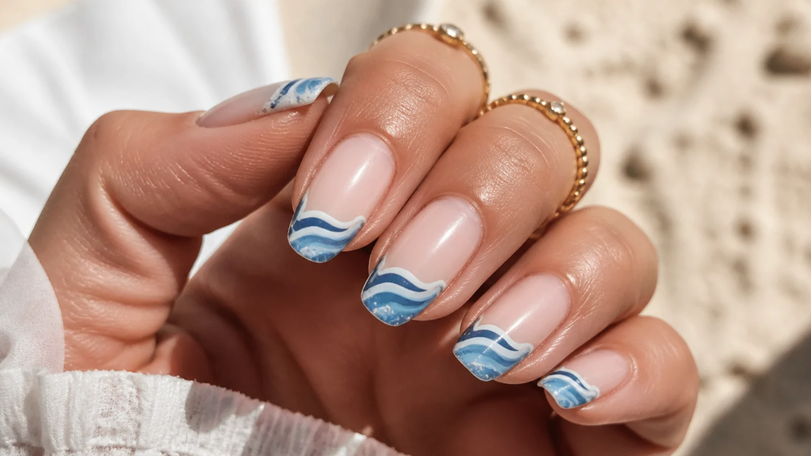 Close-up of a blue wave manicure with a slightly worn tip after several beach days