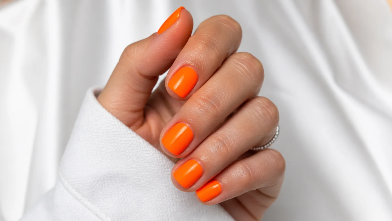 Short square neon orange summer nails in a vivid tangerine gloss
