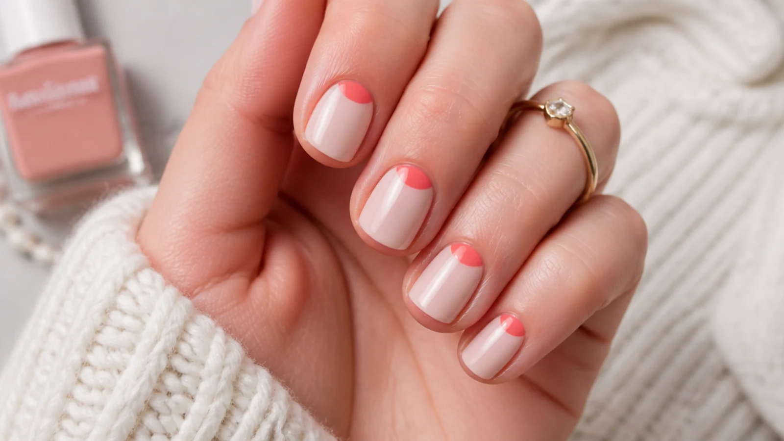 Short round nails with a thin coral half-moon painted at the cuticle instead of the tip