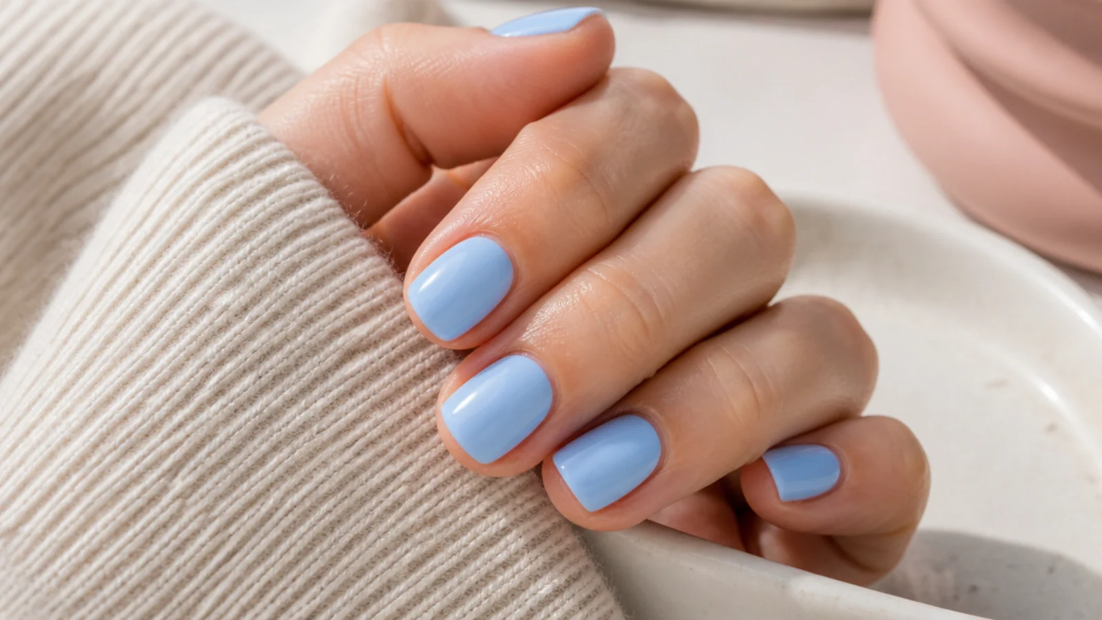 Short round nails in a soft opaque sky blue cream with a clean glossy finish